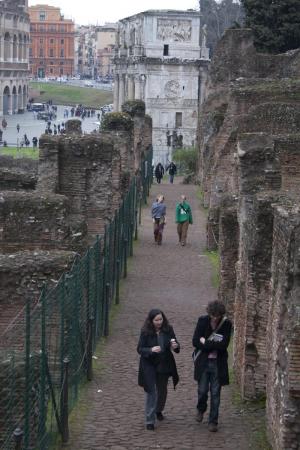 Faculty and students explore ruins on the Palatine Hill, with the arch of Constantine and the Colosseum in the background.