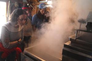 Biology professor Jaime Tanner stops to smell the syrup during a visit to neighbors Alan Dater and Lisa Merton’s sugar house in April with her winter ecology class. Students in the class, called Life in the Cold, also helped Alan and Lisa collect sap from maple trees on campus.