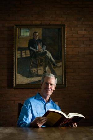 President Kevin checks out a library book, with a portrait of former president Rod Gander looking on. Photo by Kelly Fletcher