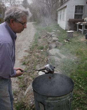 Retired economics professor Jim Tober frequently haunted the ceramics studio last spring. Here he was found testing the results of a raku firing, which is always more surprising than economics.