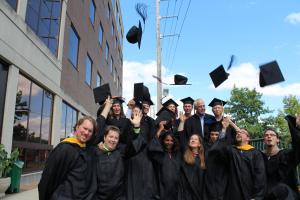 Some graduates and faculty play “toss the mortarboard” during the reception at the graduate center.