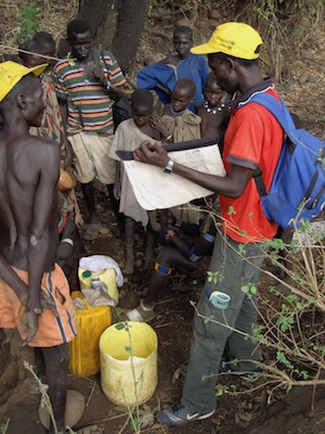 A field officer in South Sudan uses pictures to discuss Guinea worm disease transmission with community members.